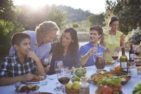 A family gathered at a picnic table, mountains in the background