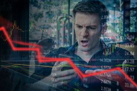 一名沮丧的男子正看着他的手机，上面覆盖着向下的红色趋势线和股票行情符号