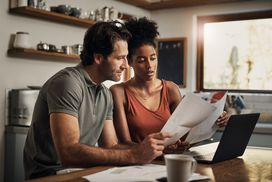 一对深情的年轻夫妇一边在家做预算，一边处理文件。