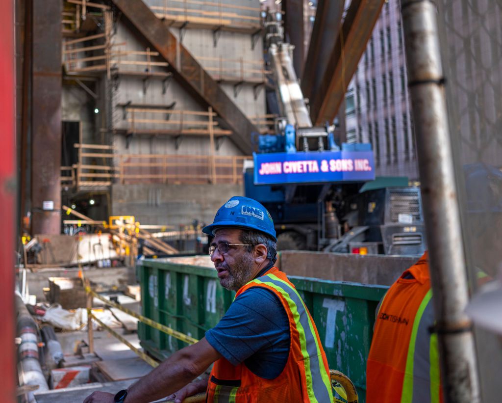 摩天大楼的建筑工人在一个蓝色安全帽戴眼镜
