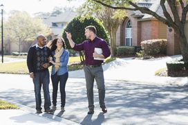 Couple standing outside on a residential block looking at the area with a realtor