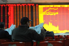 Man reading newspaper at stock exchange, representing short selling stock.