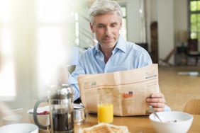 老男人一边吃早餐一边看报纸
