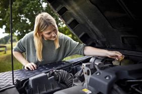 年轻女子检查汽车与打开引擎盖