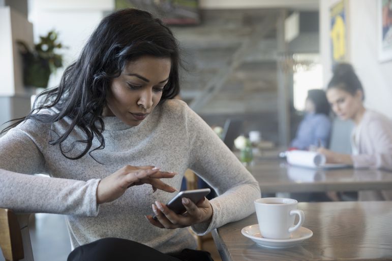 女人在咖啡馆里用智能手机喝咖啡