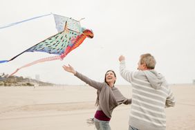 一对中年男女在海滩上放彩色风筝