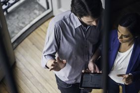 A man and a woman review a homeâs details on a tablet computer screen.