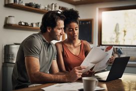 A couple reviews paperwork in a clean, well-lighted kitchen.