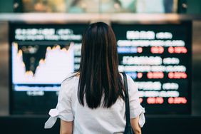 后视图的商人在证券交易所市场显示屏板在市中心金融区