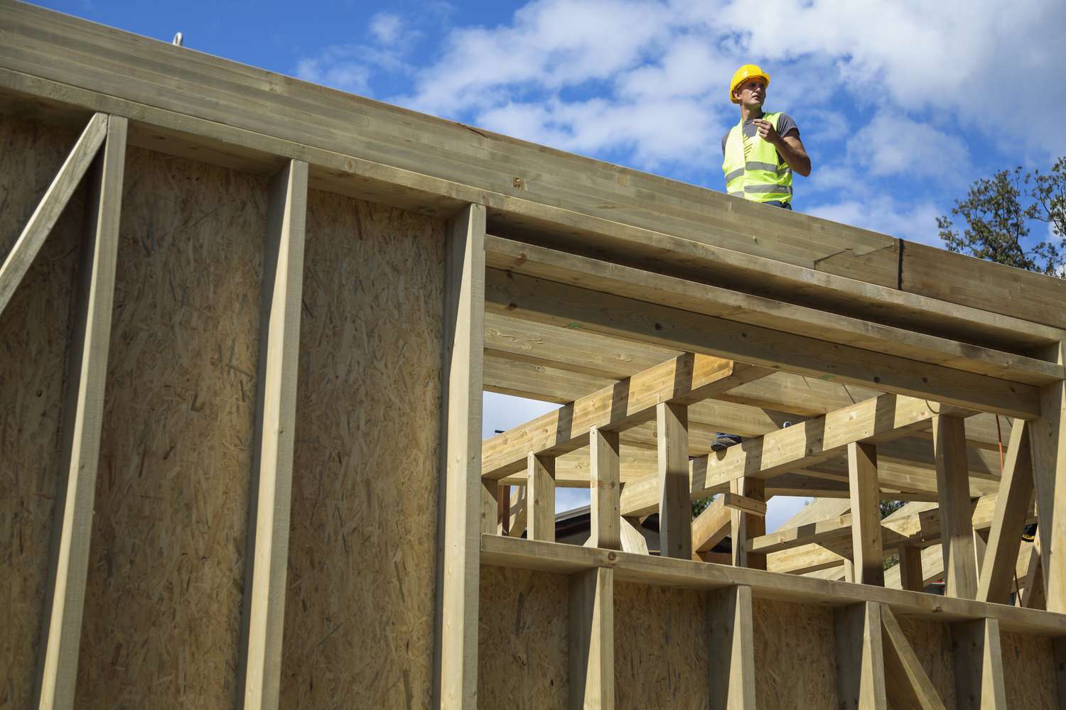一名建筑工人站在一栋在建的新房顶上。