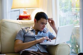 年轻人在客厅的笔记本电脑上研究投资选择