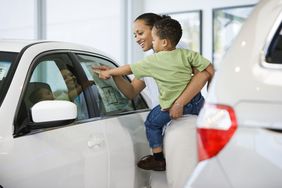 一位顾客抱着一个蹒跚学步的孩子看着一辆新车上的门罗尼贴纸。