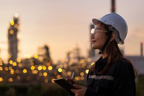 工人在石油和天然气工业石油炼油厂工程师与个人安全设备PPE检验按照清单的平板电脑。