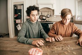 两个孩子数着放在厨房柜台上的硬币