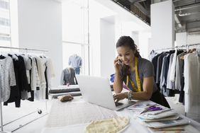一个女人在她的小型服装设计公司的笔记本电脑前工作