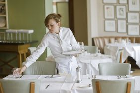 餐馆里，服务员在桌子上摆水杯。