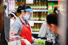 超市收银员在医学防护面具在结帐工作