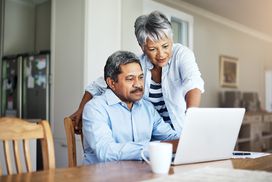 一对老年夫妇使用笔记本电脑的照片＂width=