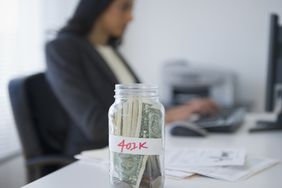 一个标着401k的罐子里面装满了钱还有一个在后台工作的女人