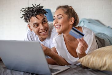 几个微笑,因为他们使用信用卡购买笔记本电脑躺在床上