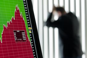 电脑显示器上暴跌的股票屏幕，背景是一位忧心忡忡的保证金交易员靠在窗户上