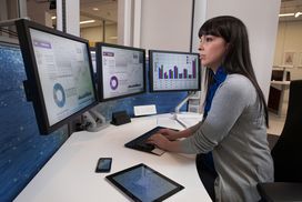 金融分析师使用多个电脑屏幕、平板电脑和智能手机在一个工作站。”width=