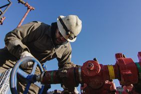 一名石油工人在一个钻井平台上泵下管线。