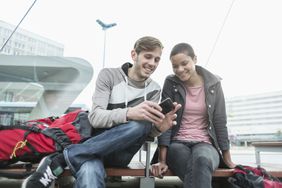 年轻夫妇在公交车站用智能手机
