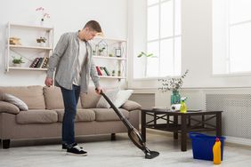 年轻人用吸尘器打扫房子