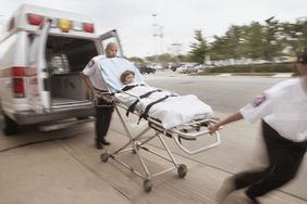模糊的紧急医疗技术人员推着一个轮床，上面有一个病人远离救护车