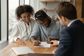 Couple signing paperwork in office with lawyer