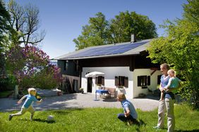 一家人在他们有太阳能电池板系统的房子前面玩耍