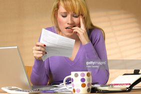 一位女士在她的办公桌边啃指甲边读账单/通知