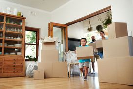 Young family of three carrying moving boxes into their new home.