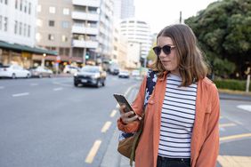 一名女子在城市街道上使用一款众包应用。