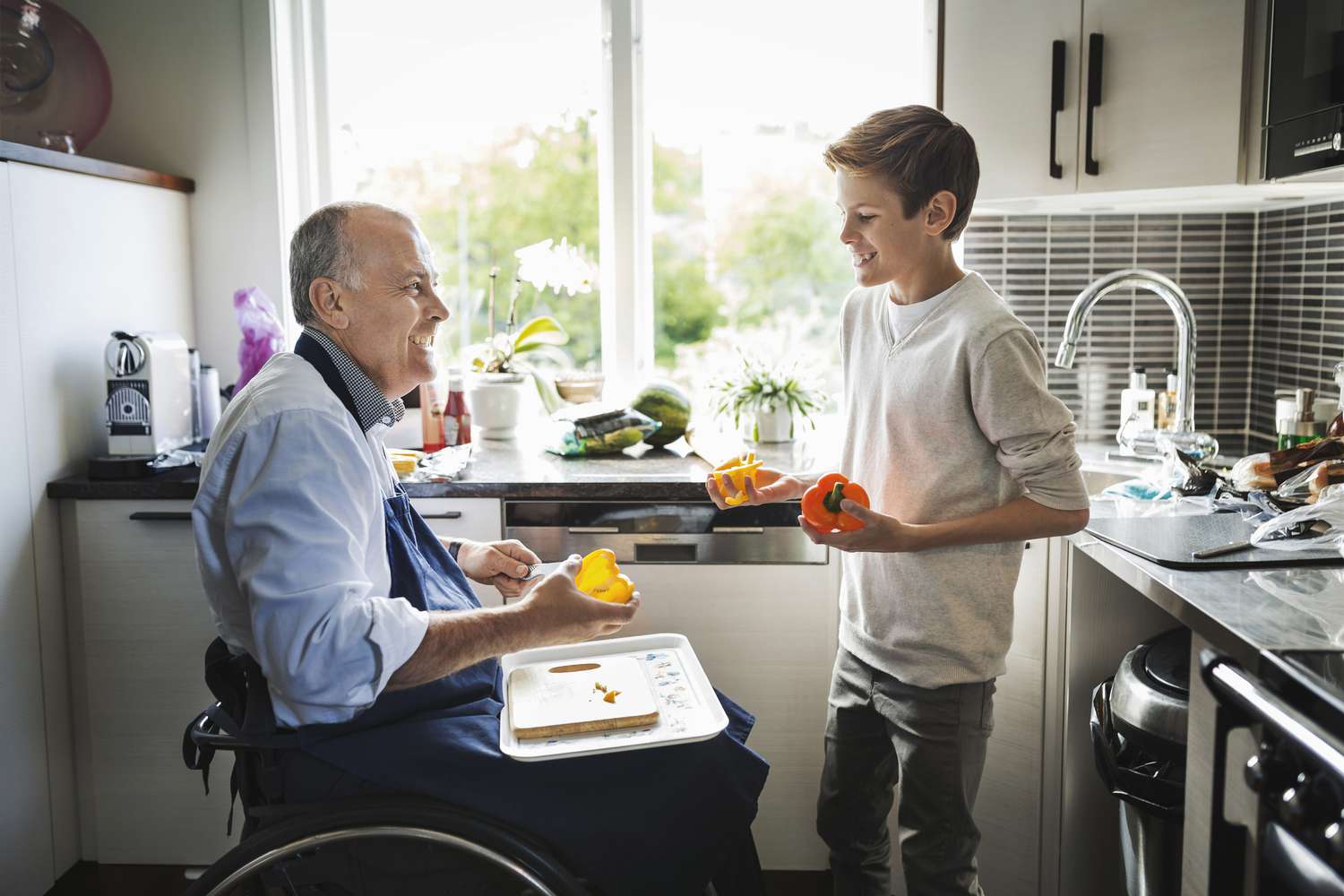 残疾退休人员和孙子在厨房准备食物＂class=