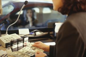 在信用合作社的免下车餐厅，女柜员正在为女顾客计算提款