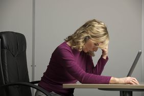 办公桌前的女人，低着头在电脑前，独自应对工作场所的非法报复