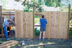 两个木匠在住宅之间建造木栅栏