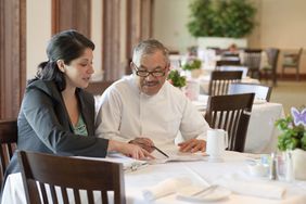 A man and a woman sit at a table at a restaurant going over business paperwork