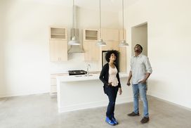 年轻夫妇在新房子的空厨房＂width=