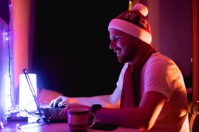 戴着圣诞帽的快乐男子在笔记本电脑上交易