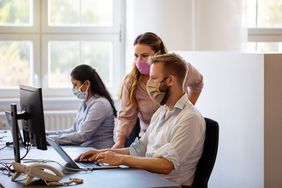 戴着口罩的商务人士在办公室里共同工作。