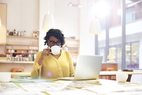 有创意的女人在办公桌前喝咖啡