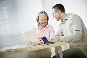 Mature couple doing paperwork using laptop