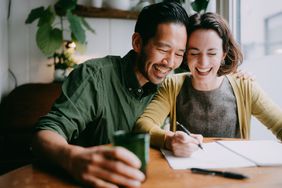 Two people laugh together at a table.