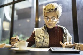 一位女士坐在咖啡馆里，用平板电脑查看她的投资情况