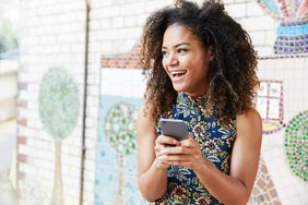 A person smiles while holding their phone.