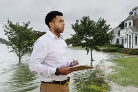 一名保险理算员拿着剪贴板调查洪水对几所房屋造成的损失