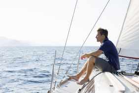 Sailor sitting on bow of sailing yacht